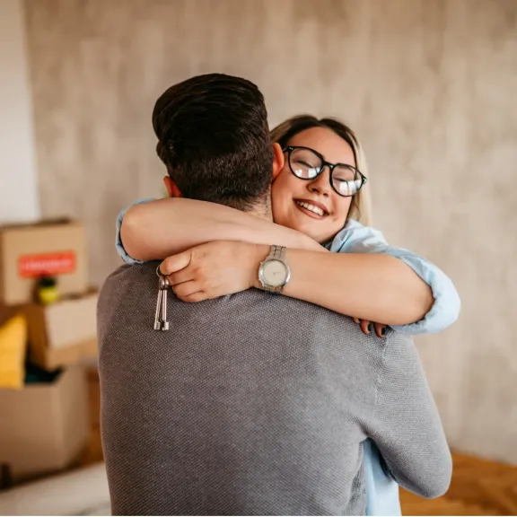 happy couple hugging and smiling with keys to new home