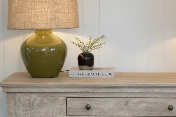 Close up of table lamp and accessories on a wooden sideboard