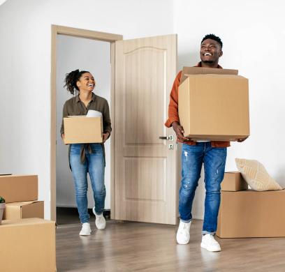 happy couple carrying boxes into home