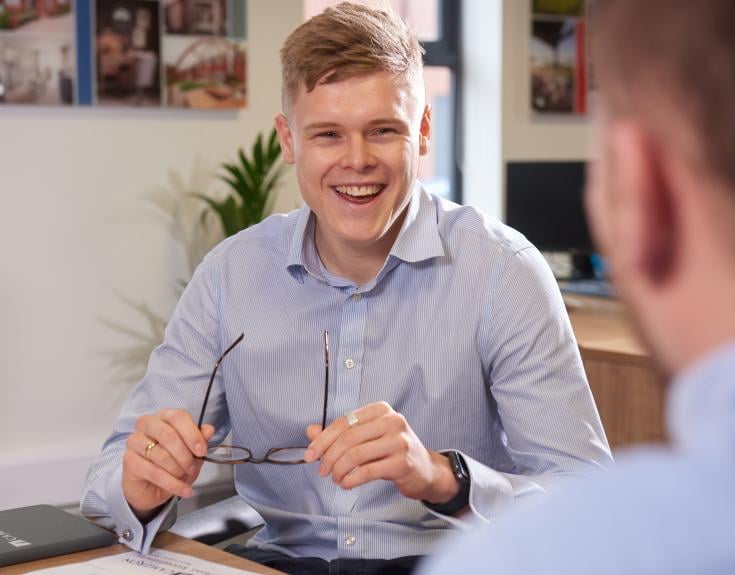 blonde white man in shirt smiling in office environment