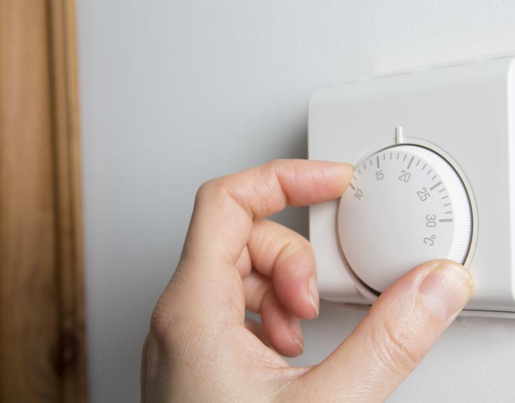 Person turning down thermostat