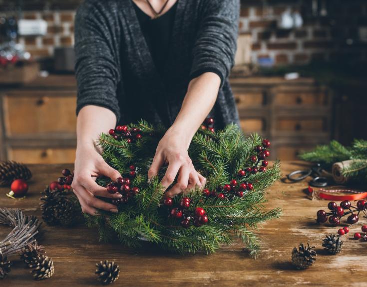Person making a Christmas wreath on a table 