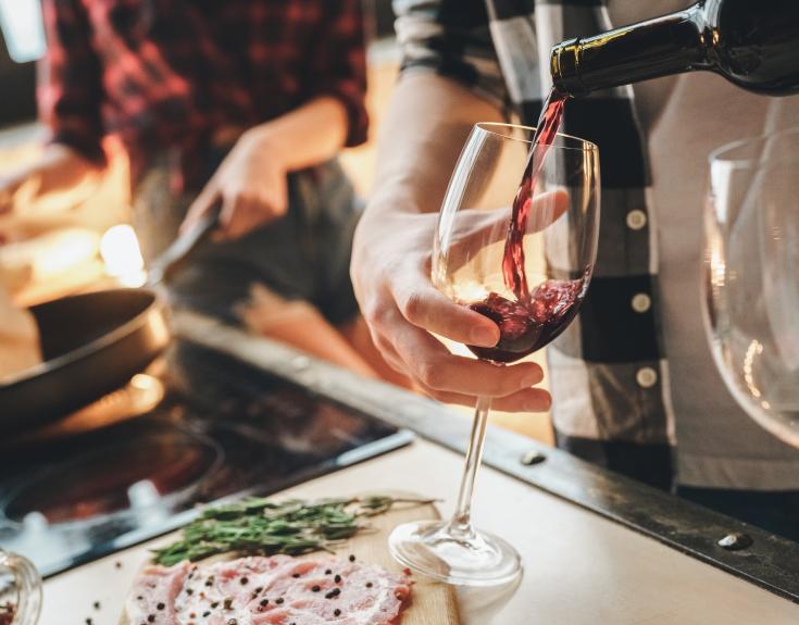 Couple cooking in the kitchen and pouring a glass of wine